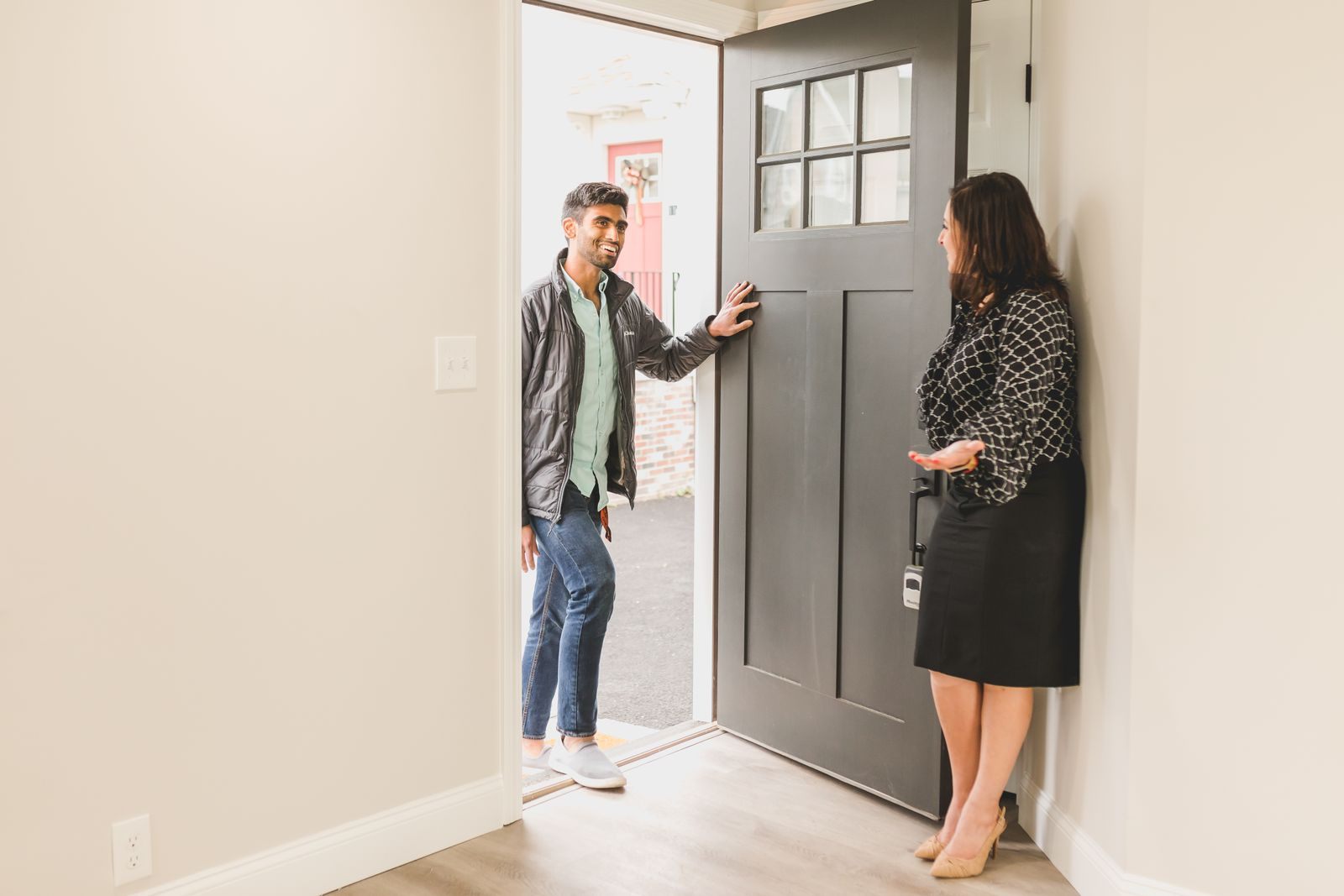 Real estate agent greeting a client at the entrance of a new home, symbolizing a welcoming embrace for potential buyers